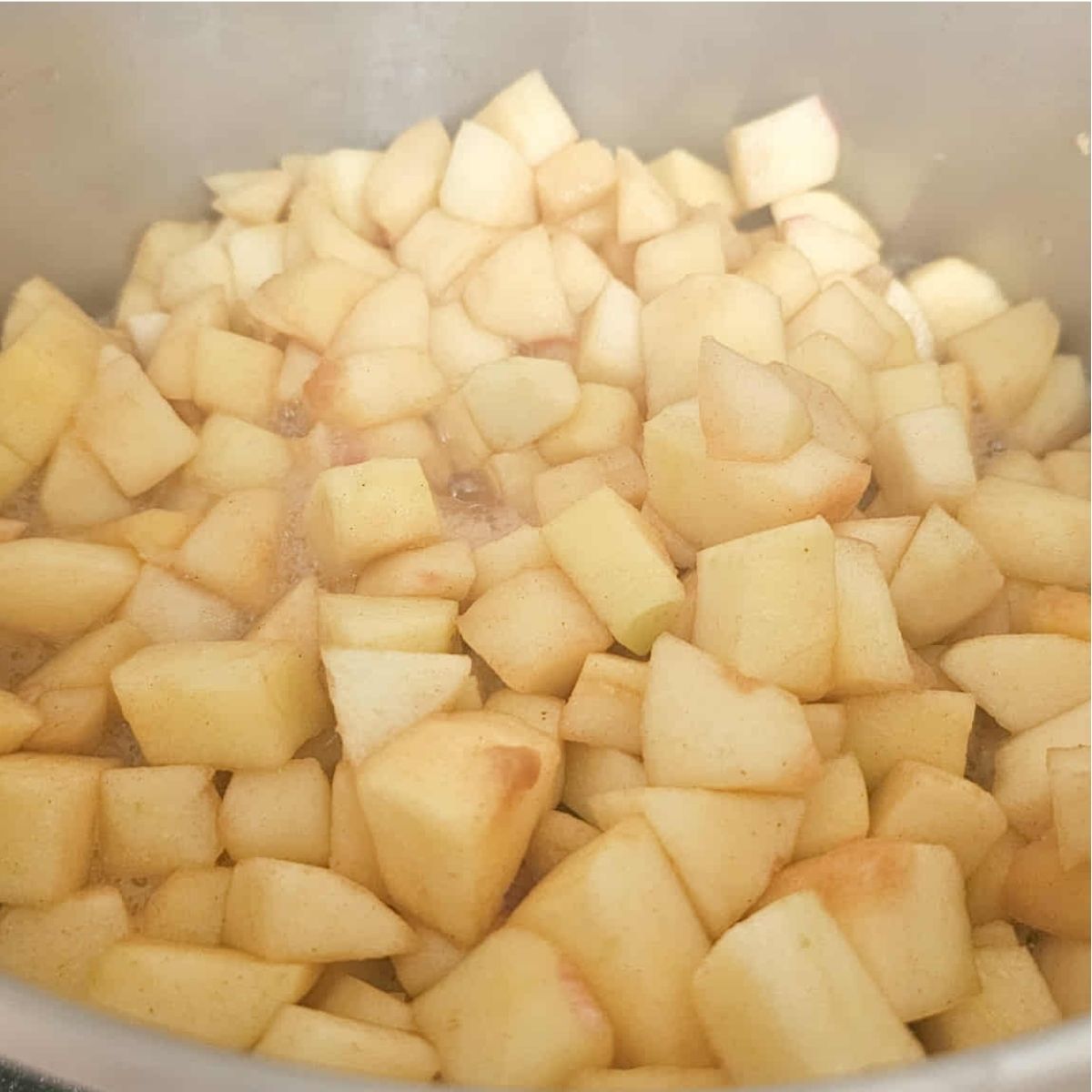 apples being cooked in a stainless steel pot