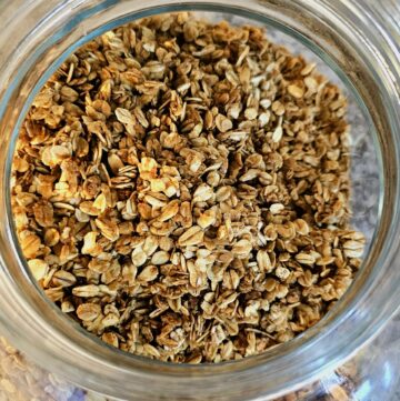 basic homemade granola sitting on a white and grey counter top in a clear jar