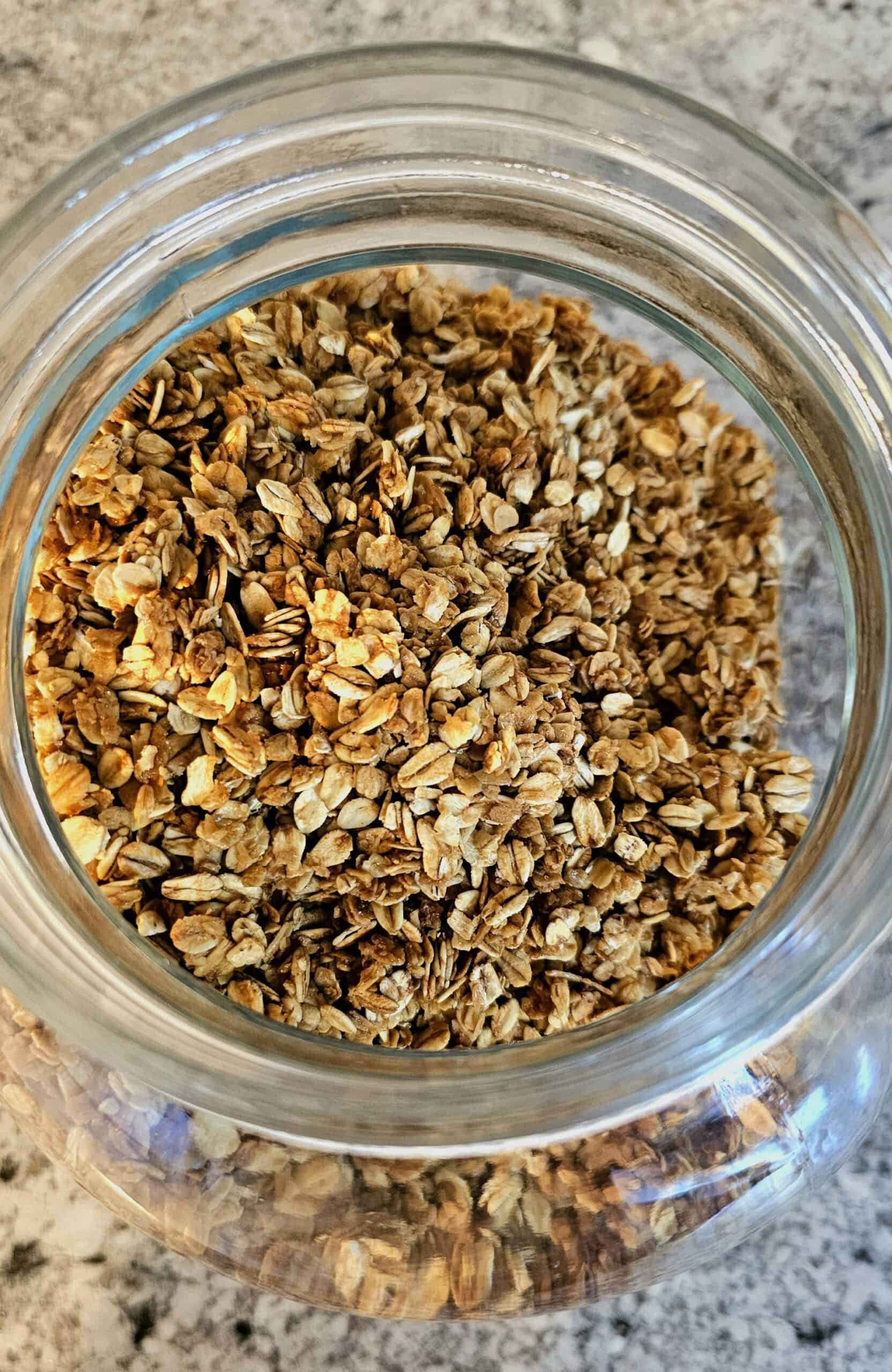 basic homemade granola sitting on a white and grey counter top in a clear jar