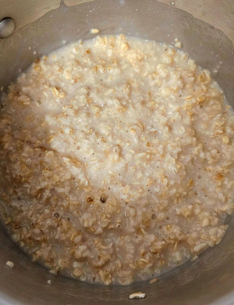 cooked oatmeal with water sitting in a stainless steel pot