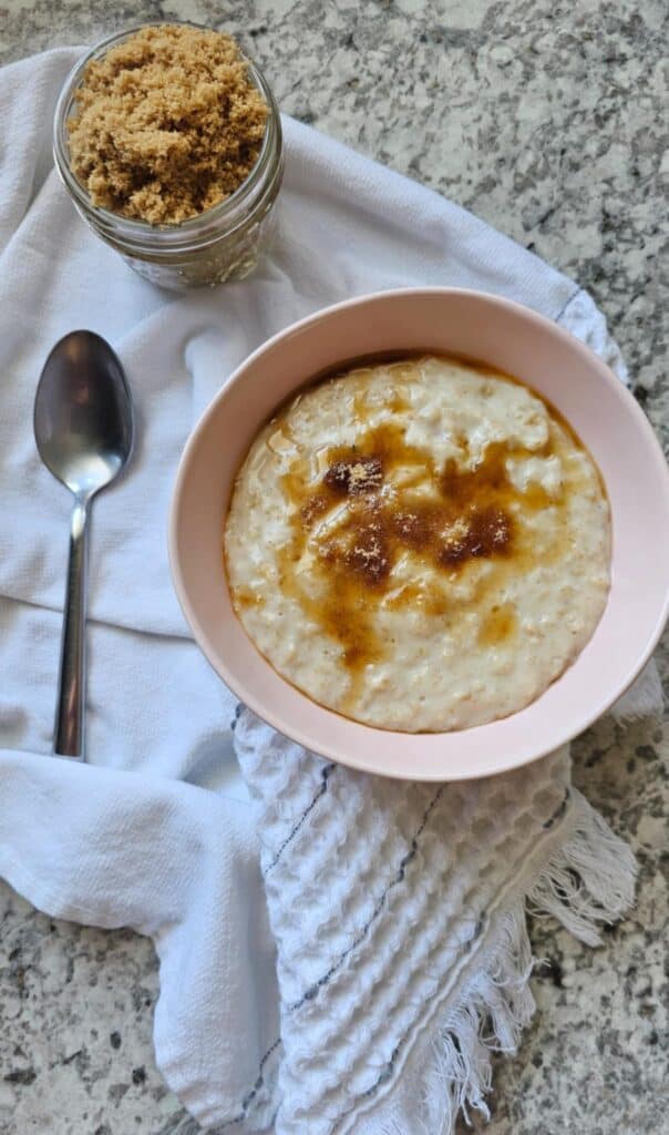 Creamy oatmeal in a oink bowl with a spoon to the left of it
