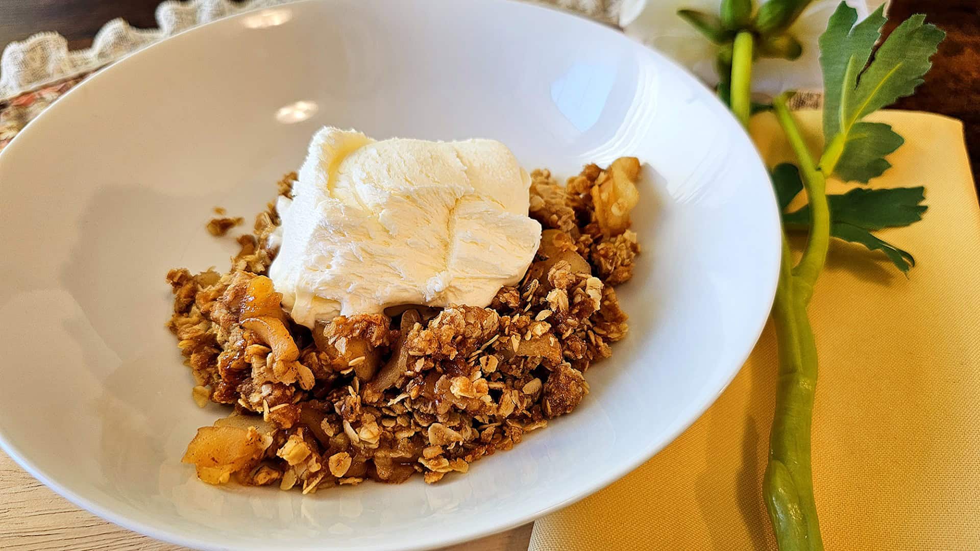 homemade apple crisp in a white bowl topped with homemade vanilla ice cream