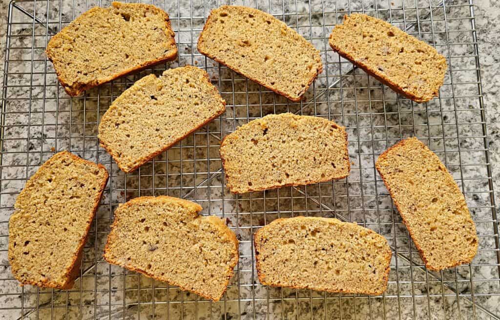 sliced up banana bread spaced apart and sitting on a cooling rack n a grey and white counter