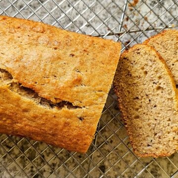 oldf fashioned banana bread sitting on a wire cooling rack on a grey and white counter top