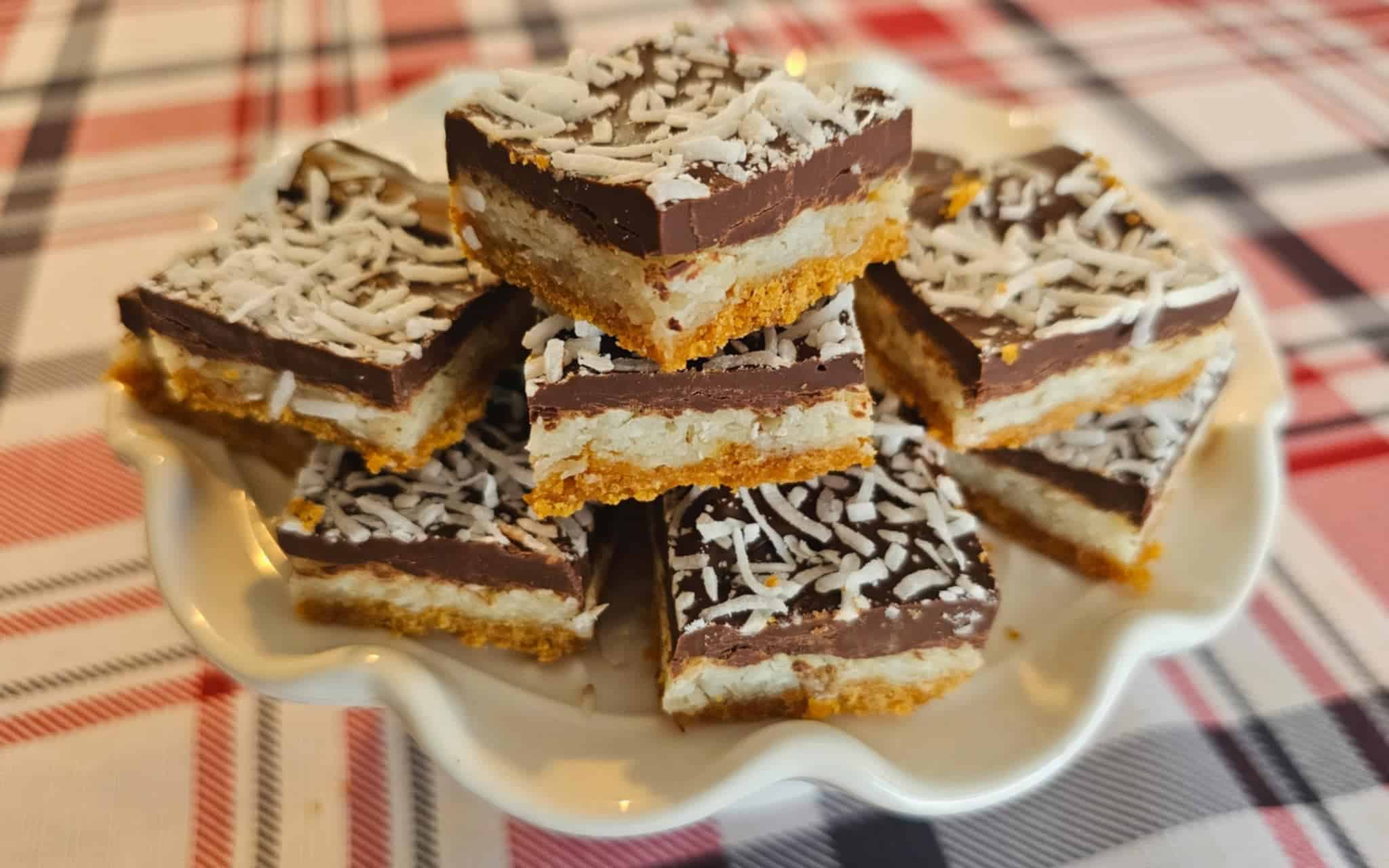 triple layer bars sitting on a vintage serving platter on a red, white and black plaid table cloth