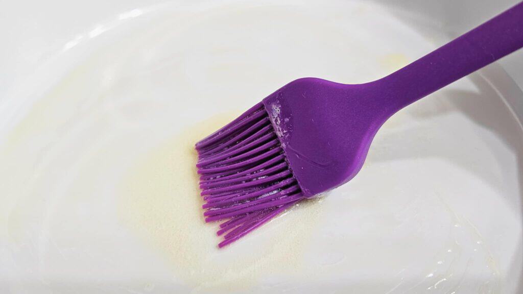 rubber spatula adding melted butter to a pie dish