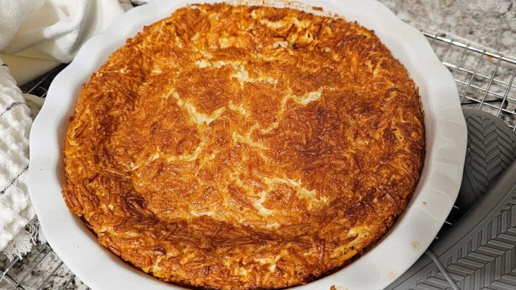 custard pie sitting in a pie dish on a cooling rack after it has cooled