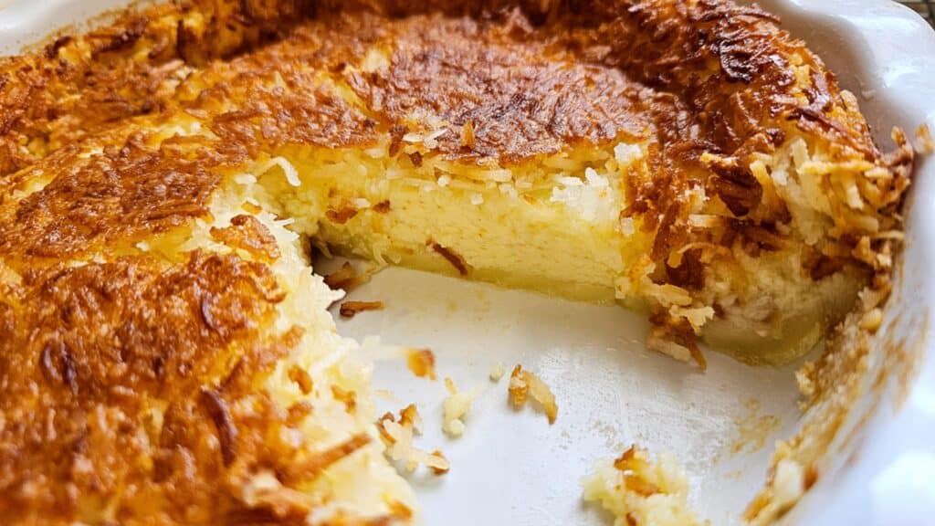 sliced Impossible Coconut Pie Recipe (without bisquick) in a pie dish looking in at the custard filling