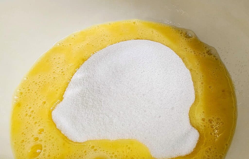 sugar about to be mixed into beaten eggs