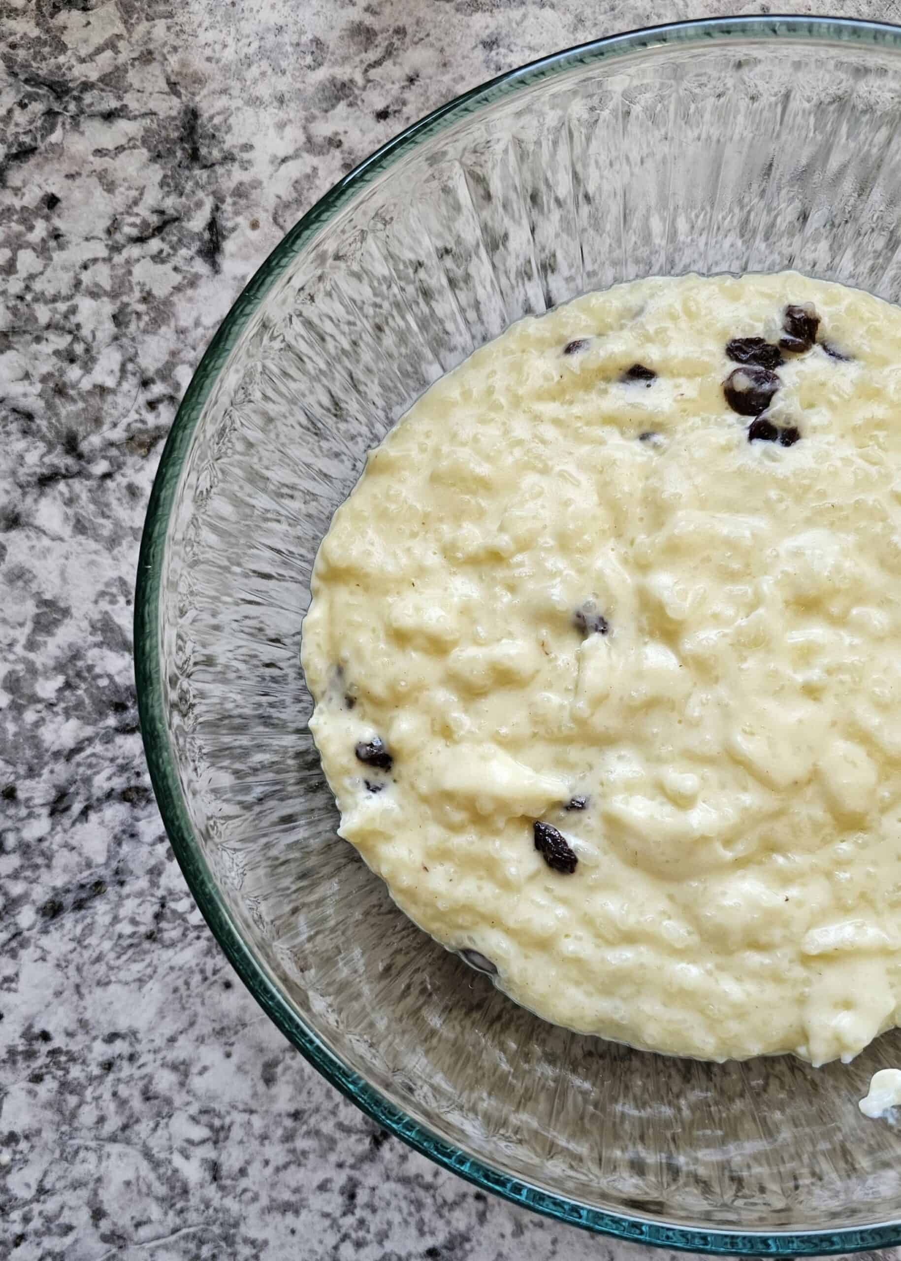 creamy rice pudding sitting in a clear large bowl with raisins