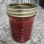 Strawberry Jam in a mason jar on a white counter with grey and black designs on it