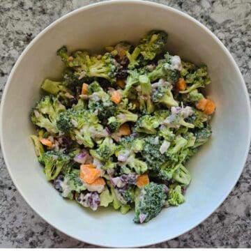 Broccoli Salad in a large white bowl on a grey counter top