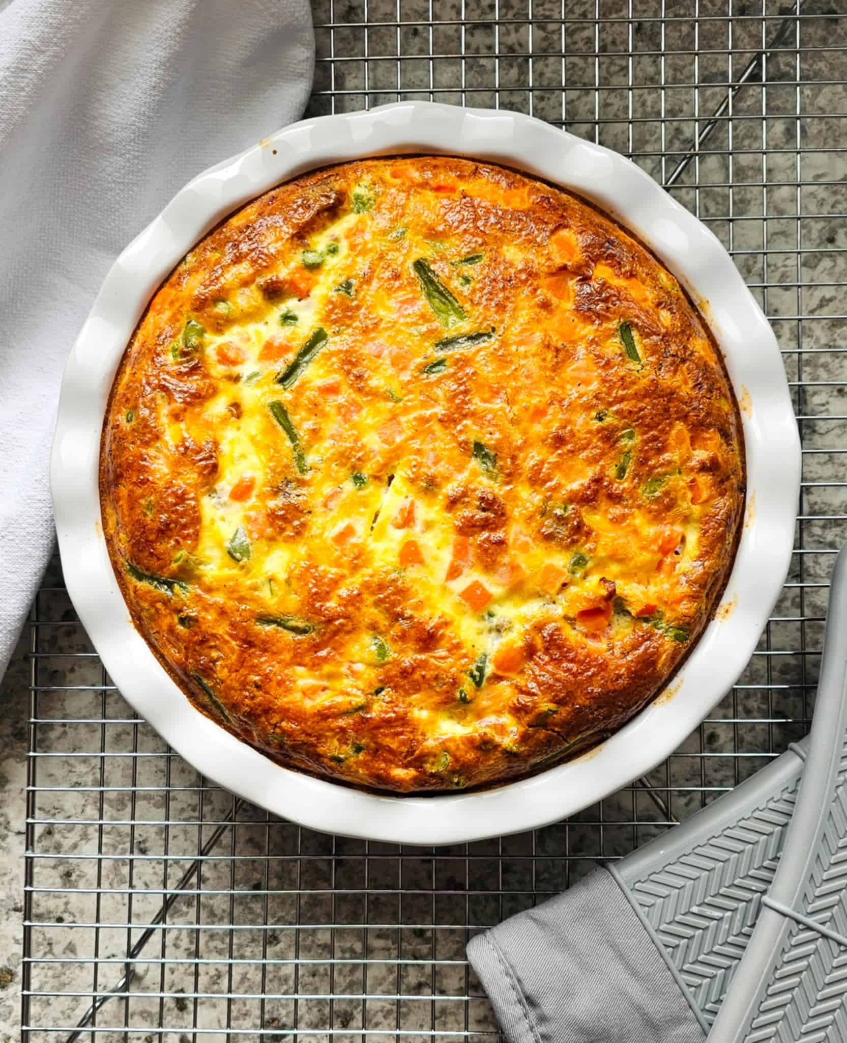 crustless quiche in a pie dish cooling on a wire rack