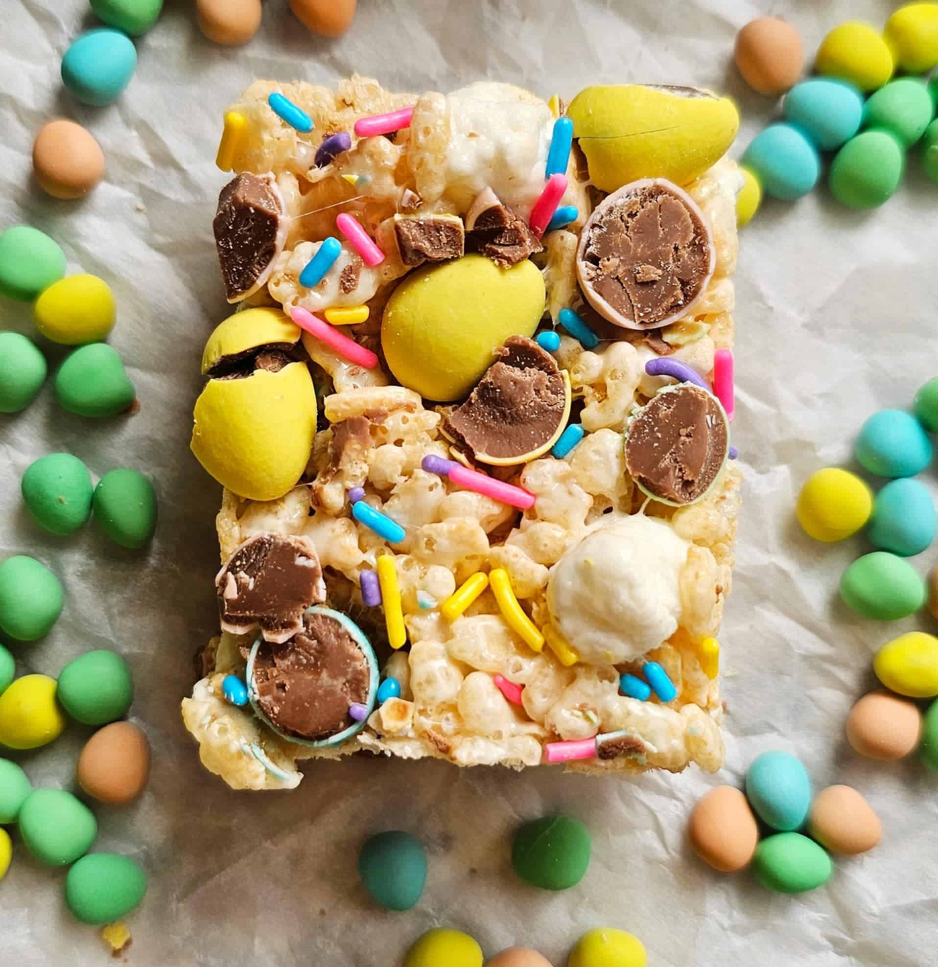 Easter rice Krispie treat on a piece of parchment paper with Cadbury eggs surrounded it