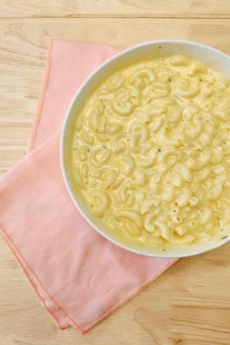 macaroni and cheese in a white glass bowl on top of a pink cloth napkin