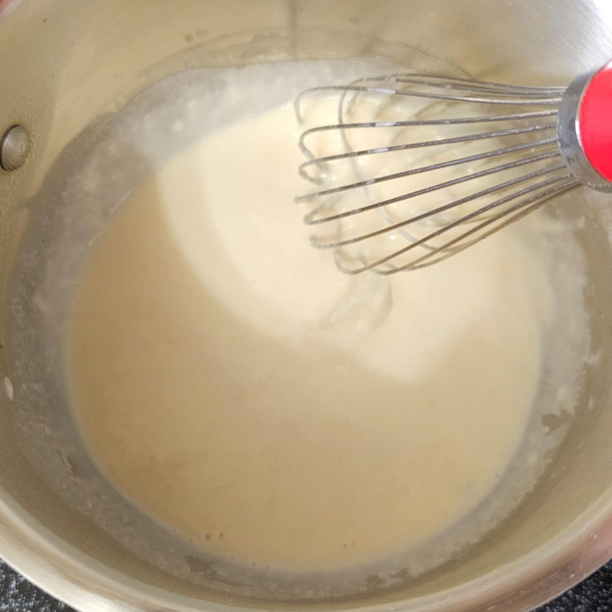 milk added to the roux in a stainless steel pot