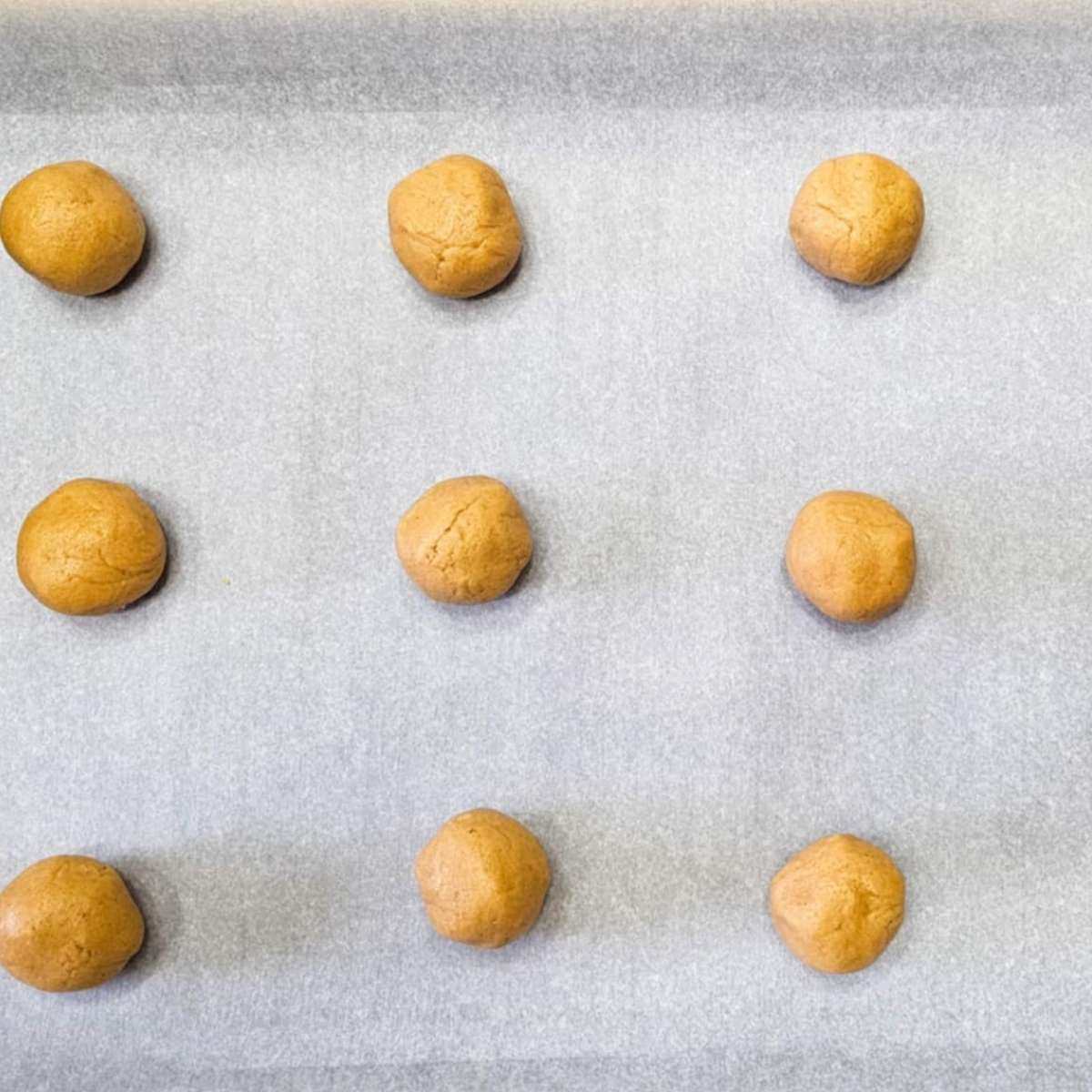 peanut butter cookie dough rolled in balls on a cookie sheet 2 inches apart