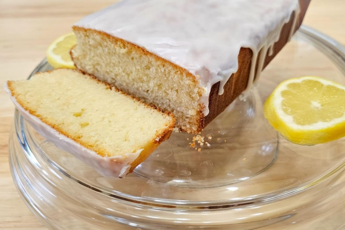 sliced lemon loaf on a serving tray with a slice of lemon next to it