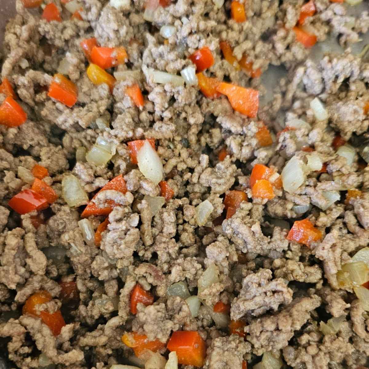 ground beef in a pan with onions and red pepper fried