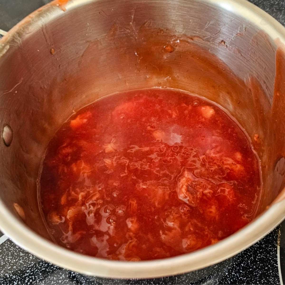 mashed cooked strawberries in a stainless stell pot