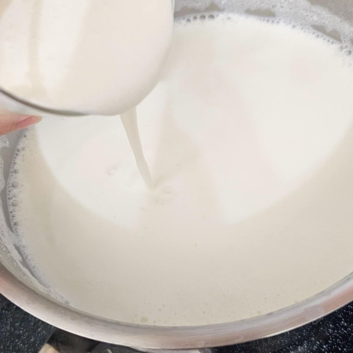 yogurt being poured into the cooled milk mixture