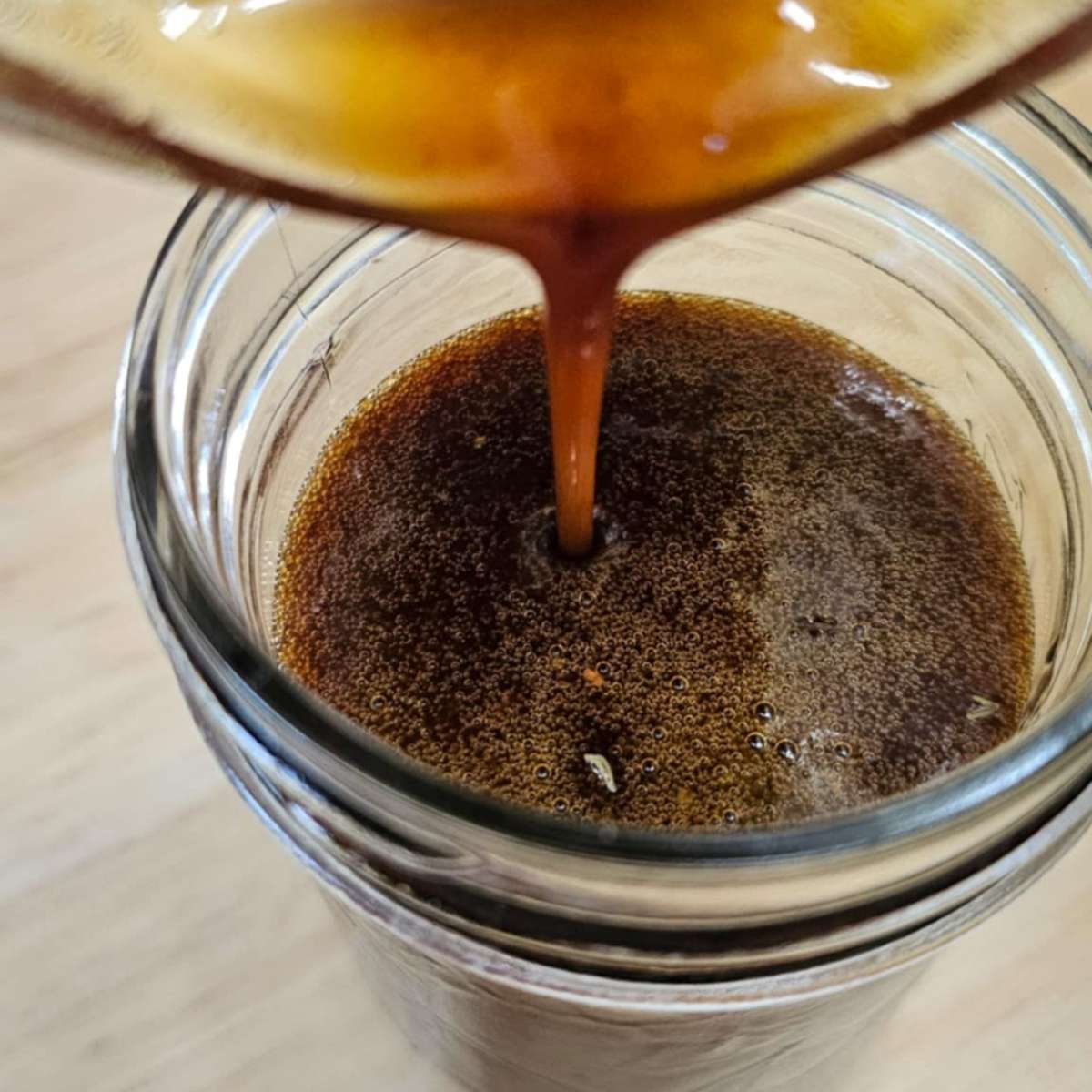 balsamic dressing being poured from a measuring cup into a mason jar