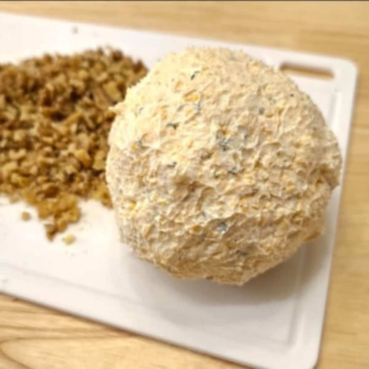 cheeseball formed and getting ready to be rolled into chopped walnuts