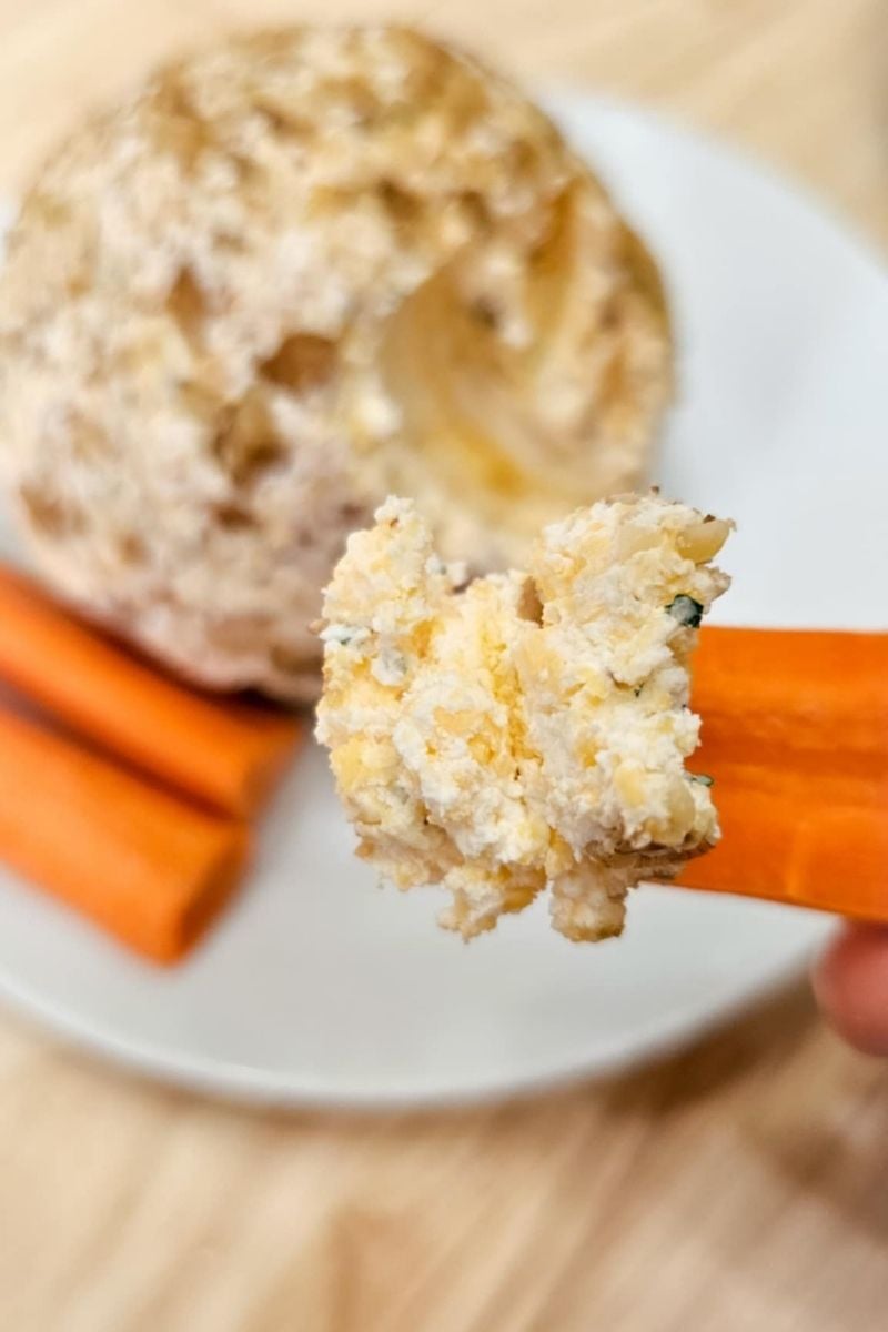 cheese ball being dipped into with sliced carrots