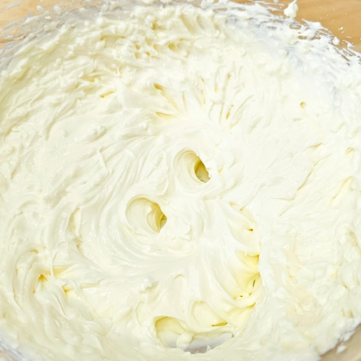 cream cheese and sour cream in a mixing bowl that was combined with an electric hand mixer