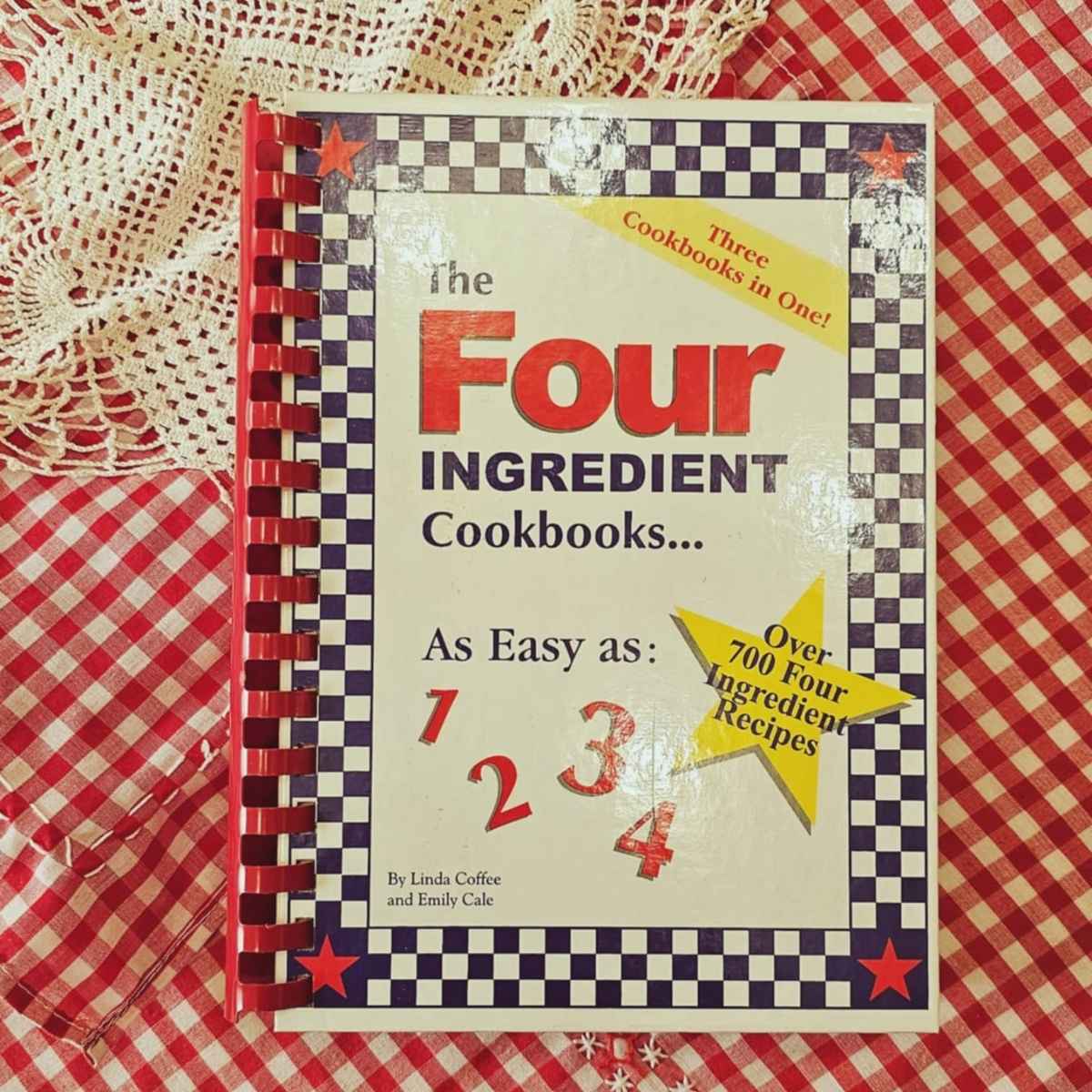 4 ingredient cookbook on a red and white table cloth with a vintage doily next to it