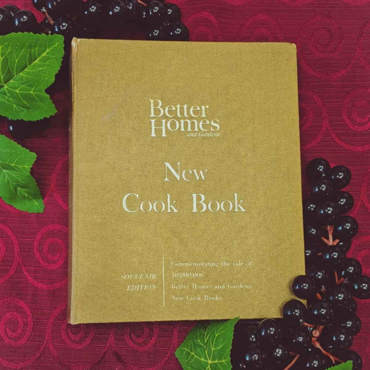 Better homes and gardens new cookbook on a red table cloth with fake grapes next to it souvenir edition