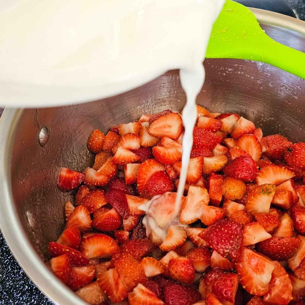 cornstarch and water mixture being poured over fresh strawberries to make sauce