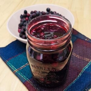 saskatoon berry sauce in a mason jar with berries in the background