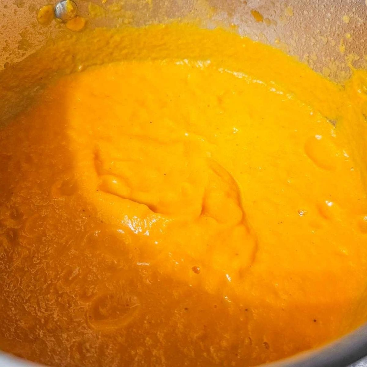 creamy carrot soup that was pureed with an immersion blender in a stainless steel pot