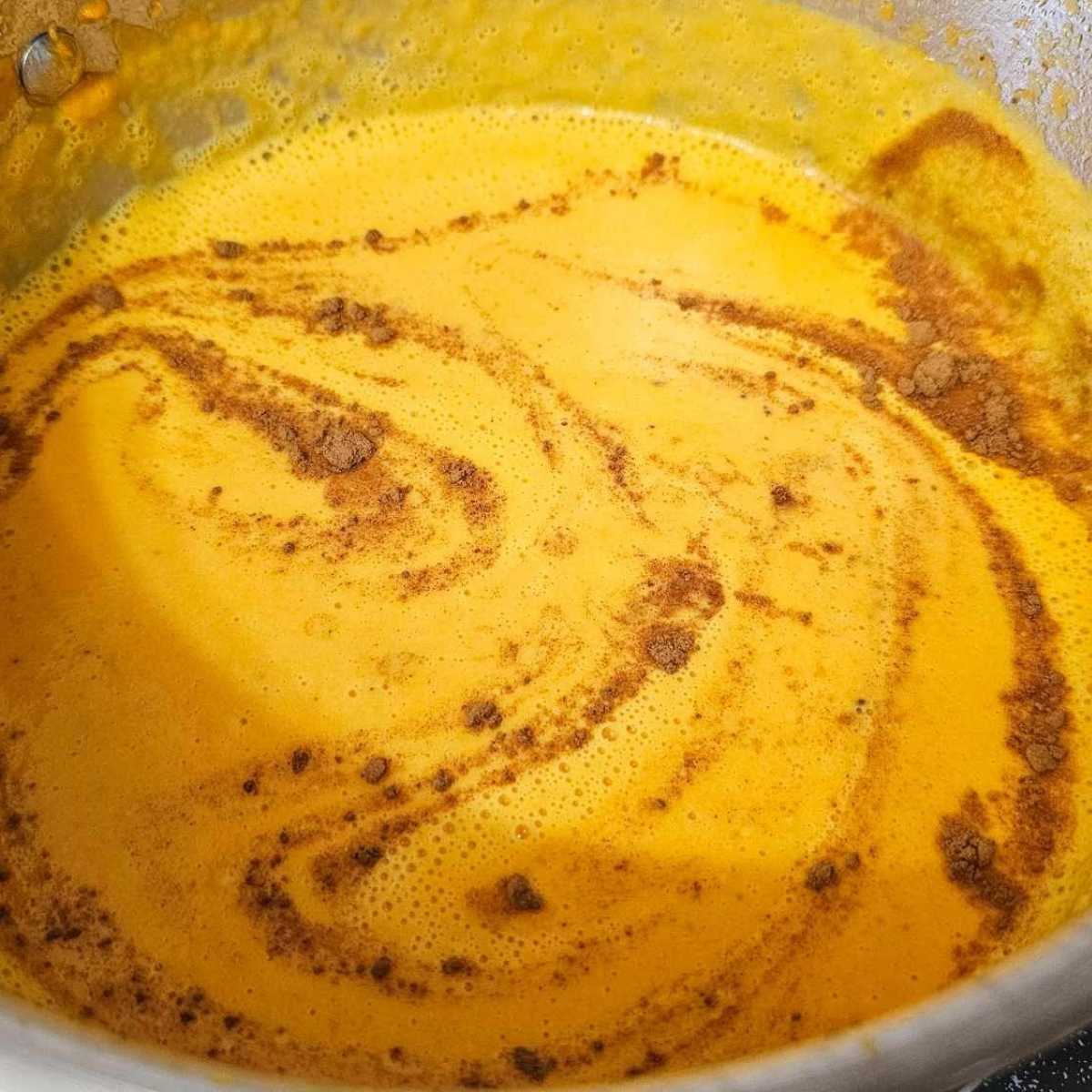 creamy carrot soup in a stainless steel pot with cinnamon