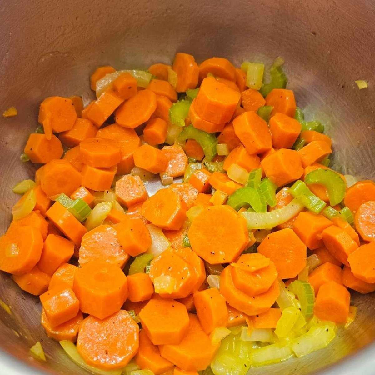 celery, carrots and onions in a pot with butter being cooked