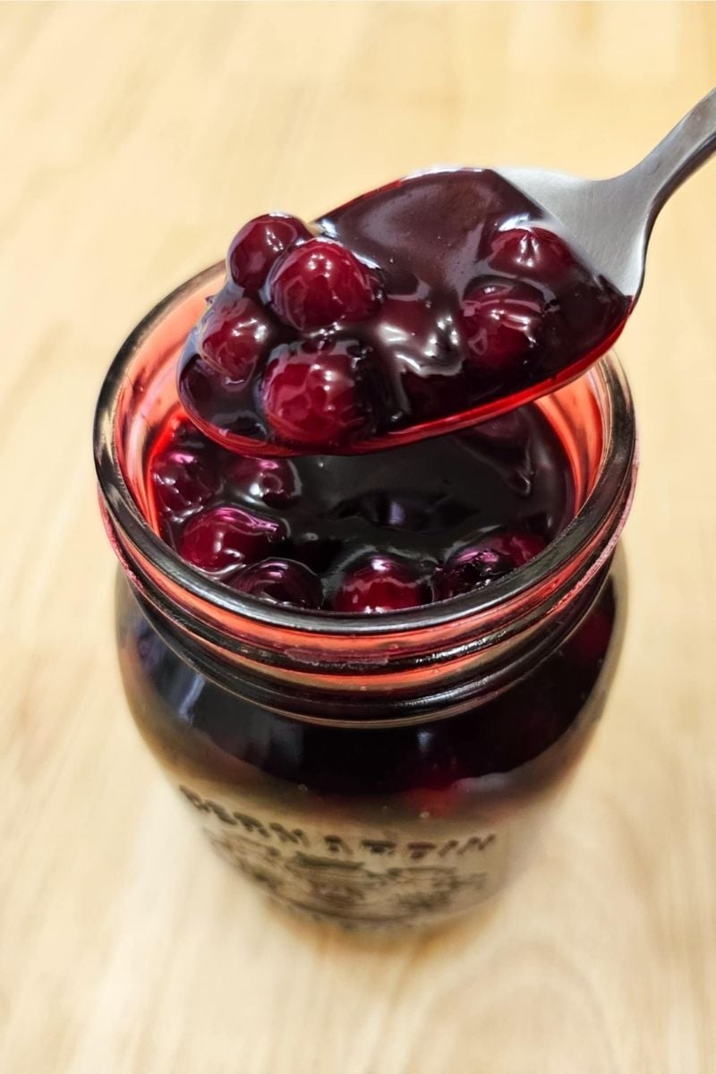 Saskatoon berry sauce in a mason jar getting scooped out by a spoon