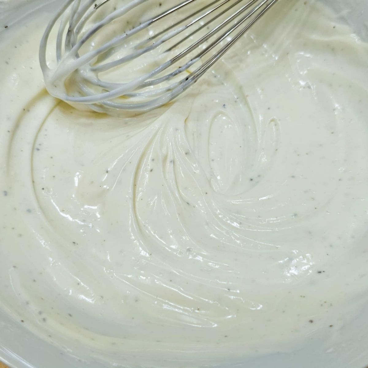 creamy cucumber dressing with sour cream that was just mixed with a whisk thats above it