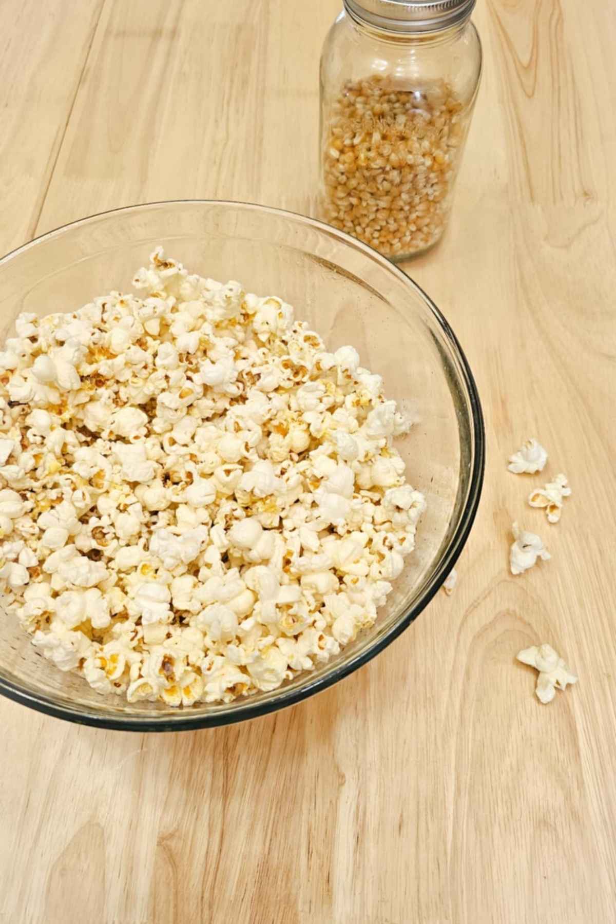 stove top popcorn in a large clear bowl on a wooden counter top