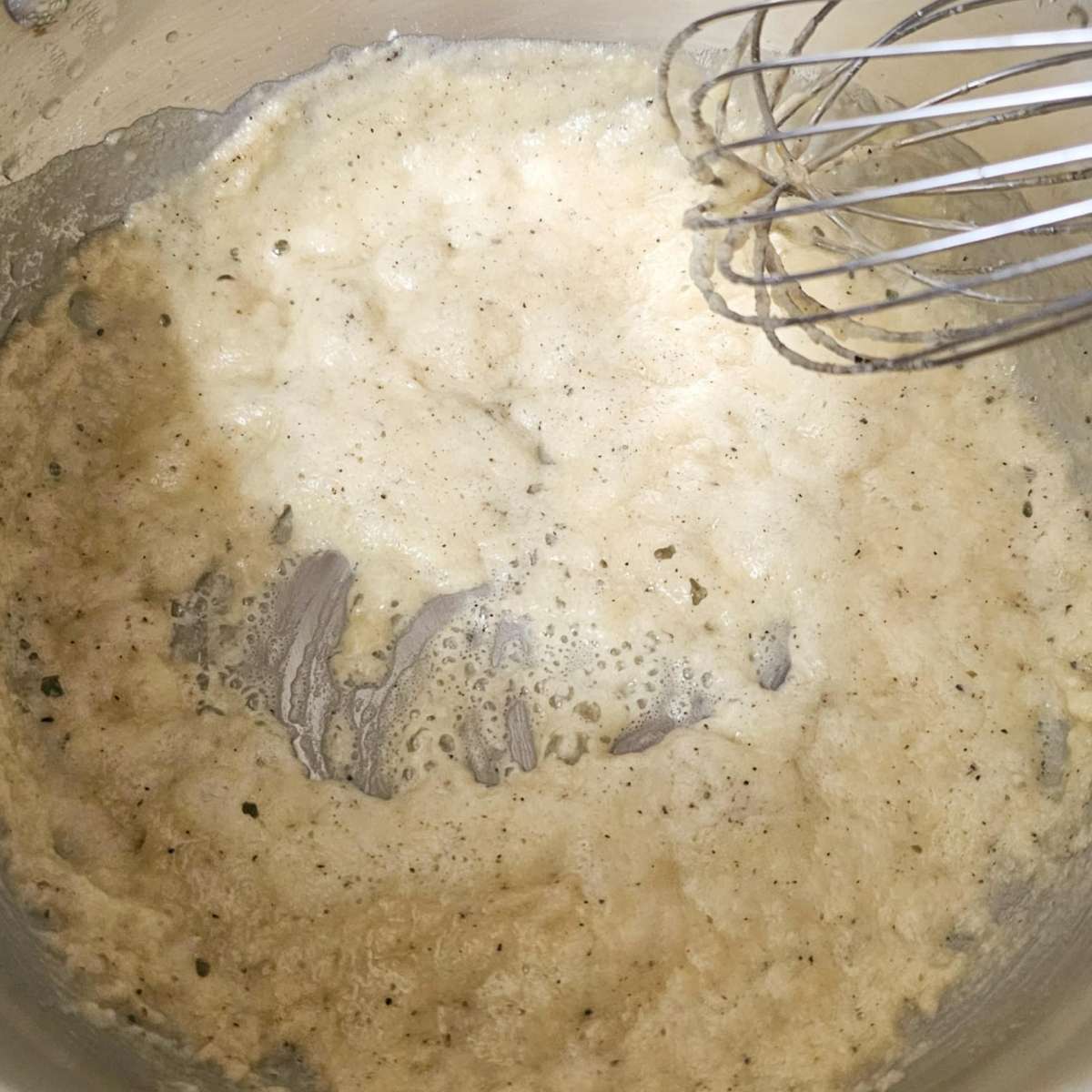 butter, flour, salt and pepper n a pot being whisked to make a roux