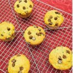 chocolate chip zucchini muffins on a wire rack sitting on a red vintage table cloth