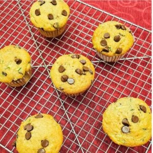 chocolate chip zucchini muffins on a wire rack sitting on a red vintage table cloth