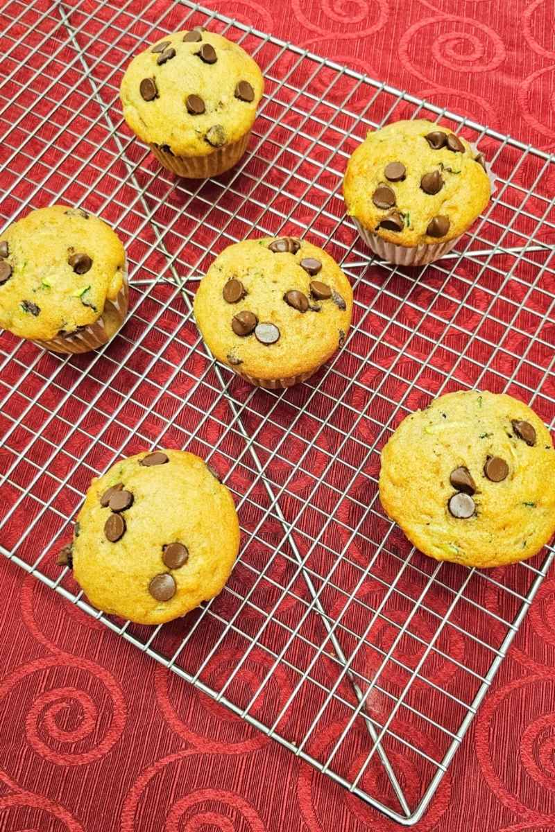 chocolate chip banana muffins on a wire rack cooling and sitting on a red table cloth