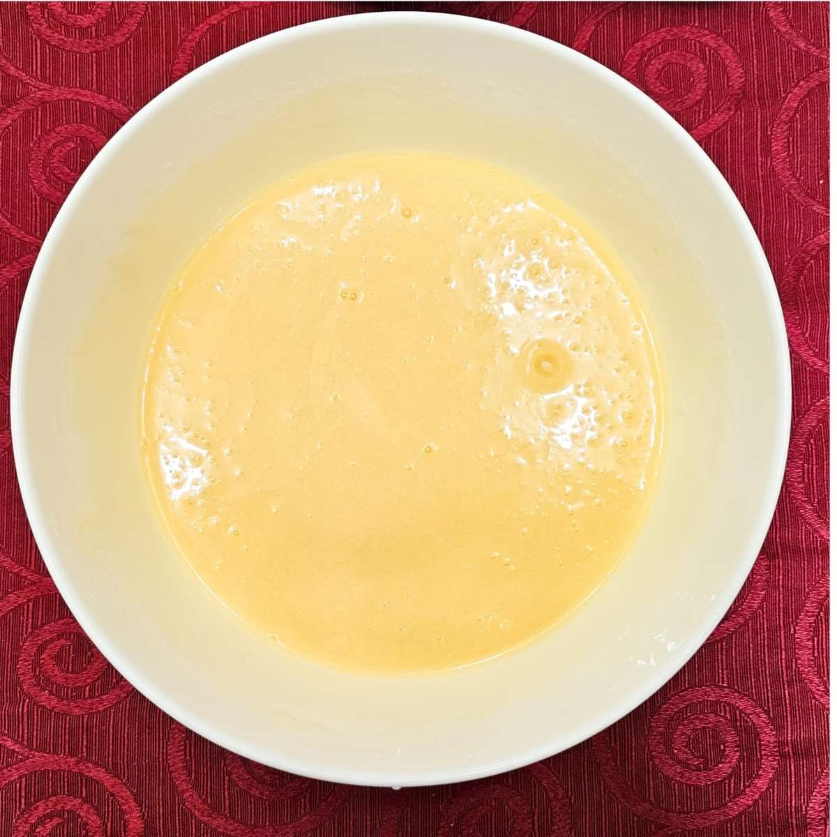 sugar, vegetable oil, egg, milk, lemon juice and vanilla extract in a white bowl on a red table cloth