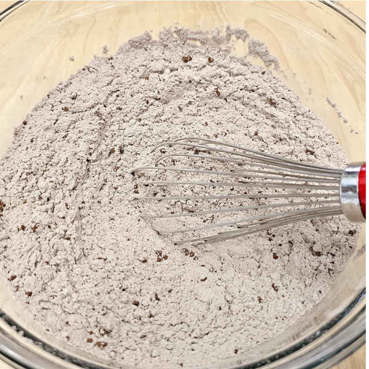 flour, cocoa, salt, baking powder, baking soda and cinnamon in a bowl with a whisk