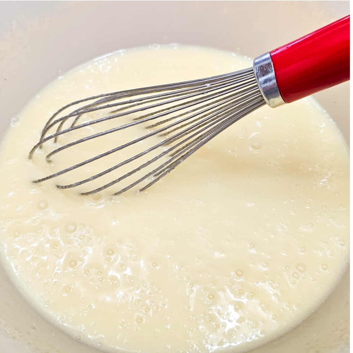 eggs, butter milk and vanilla added to other wet ingredients in a bowl with a whisk