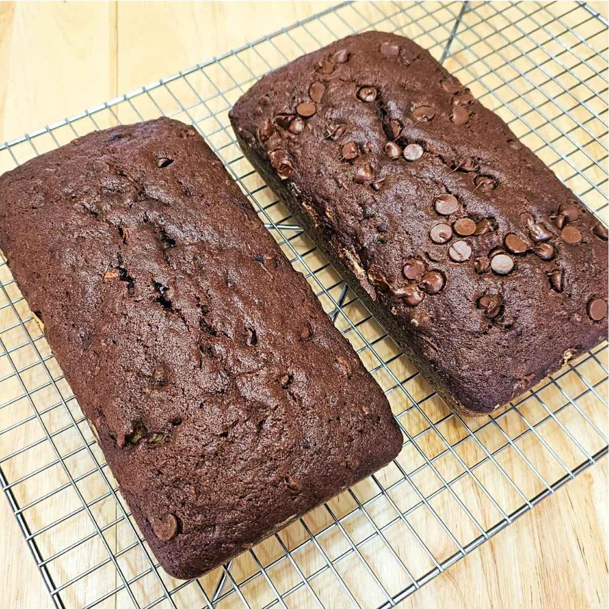 two chocolate zucchini loves sitting on a wire rack cooling