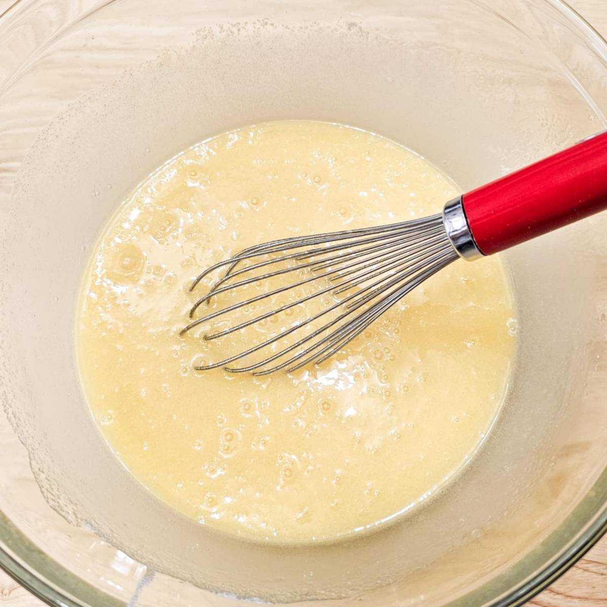 a large clear glass bowl that has eggs and sugar in it, and vegetable oil that was all mixed together