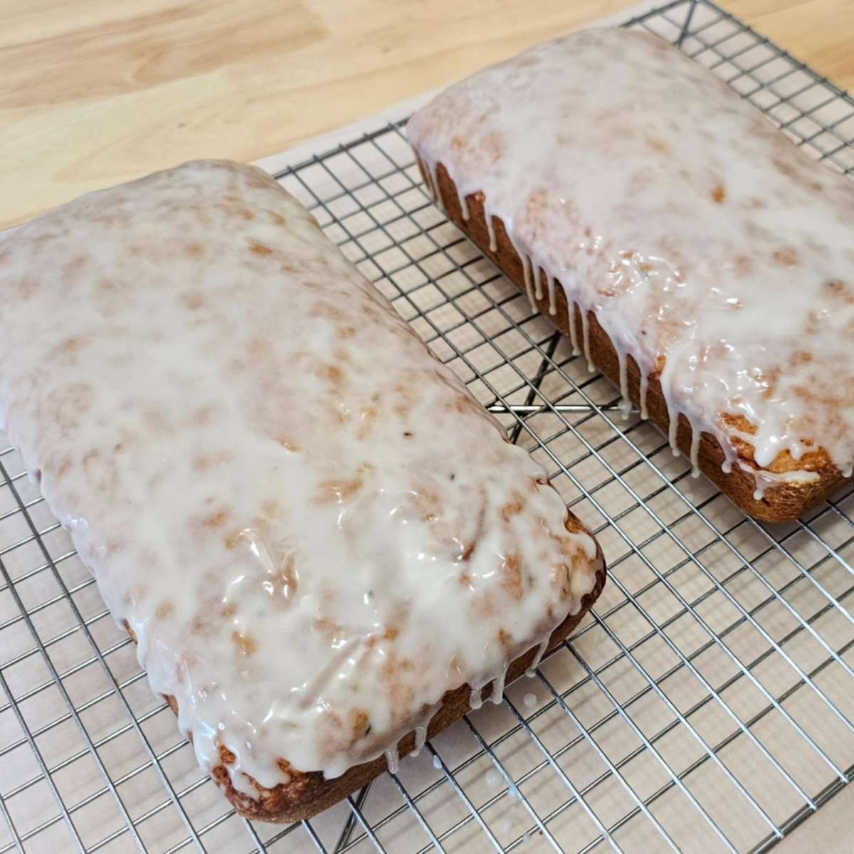 glazed lemon zucchini bread on a wire rack sitting on a wooden counter top