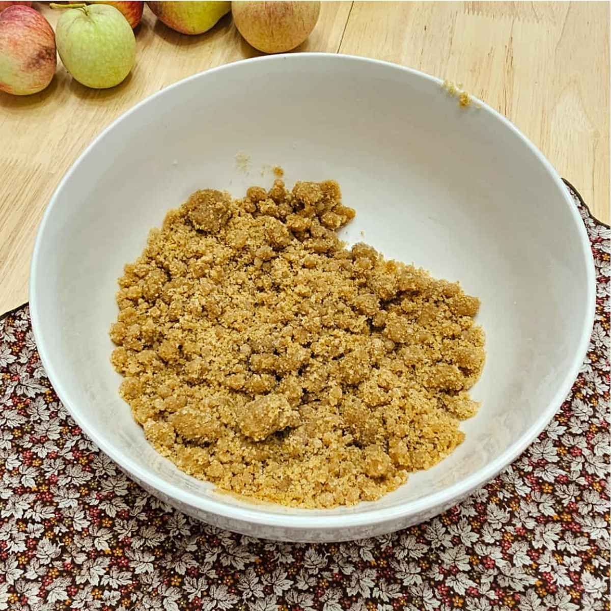 flour, sugar and cinnamon in a bowl mixed with butter to make a crumbly cake topping